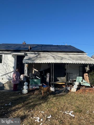 rear view of property with a yard and solar panels