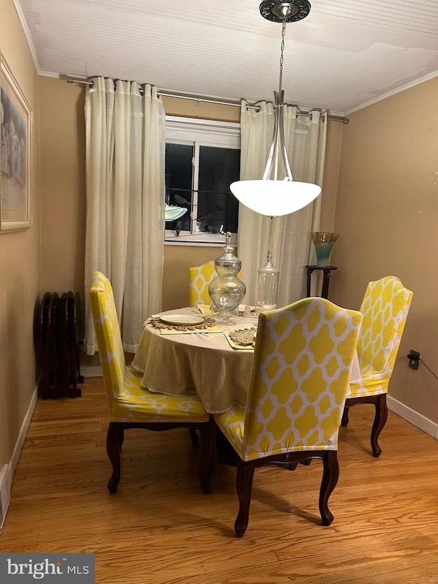 dining area featuring hardwood / wood-style flooring, radiator heating unit, and crown molding