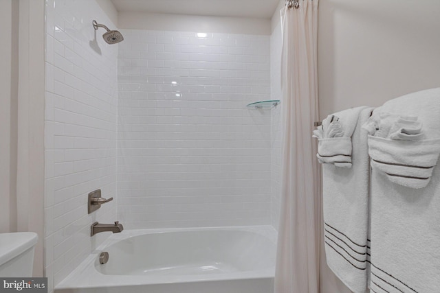 bathroom featuring shower / bathtub combination with curtain and toilet