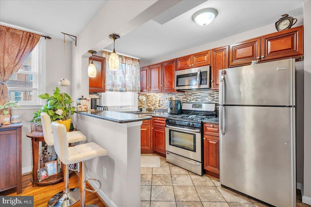 kitchen with a breakfast bar, decorative light fixtures, kitchen peninsula, stainless steel appliances, and backsplash