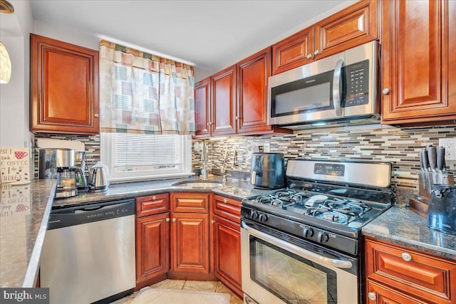 kitchen with sink, decorative backsplash, dark stone counters, light tile patterned floors, and stainless steel appliances