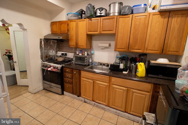 kitchen featuring light tile patterned flooring, appliances with stainless steel finishes, sink, and tasteful backsplash