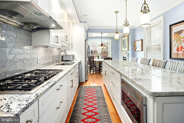 kitchen with stainless steel appliances, a kitchen island, exhaust hood, and white cabinets