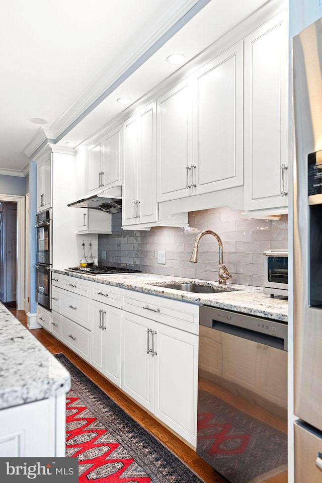 kitchen with white cabinetry, ornamental molding, stainless steel appliances, and sink