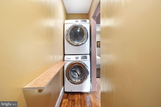 clothes washing area featuring stacked washing maching and dryer and dark wood-type flooring