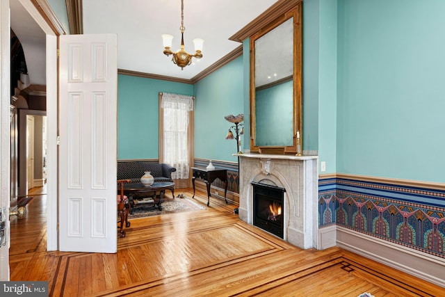 sitting room with an inviting chandelier, crown molding, a fireplace, and wood-type flooring