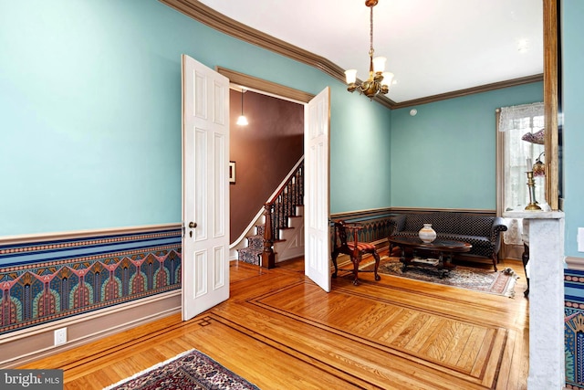 living area featuring hardwood / wood-style flooring, crown molding, and an inviting chandelier