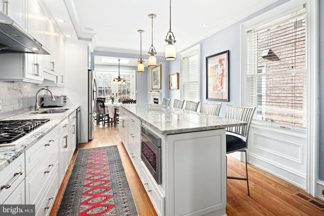 kitchen with white cabinetry, a center island, a breakfast bar, and appliances with stainless steel finishes