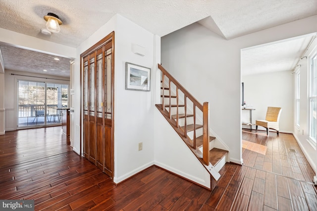 staircase with wood-type flooring and a textured ceiling