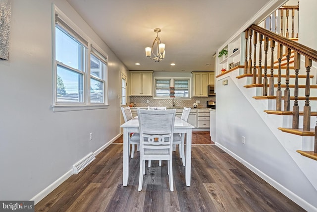 dining area with dark hardwood / wood-style floors, sink, and an inviting chandelier