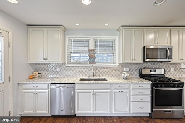 kitchen with light stone counters, stainless steel appliances, sink, and white cabinets