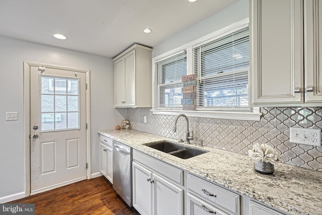 kitchen with dishwasher, sink, backsplash, light stone countertops, and dark wood-type flooring