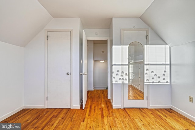 additional living space featuring vaulted ceiling and light hardwood / wood-style floors