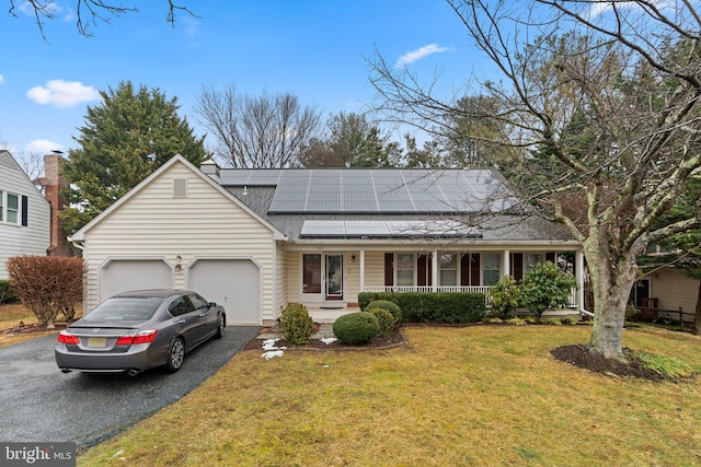 view of front of property featuring a garage, a front yard, covered porch, and solar panels