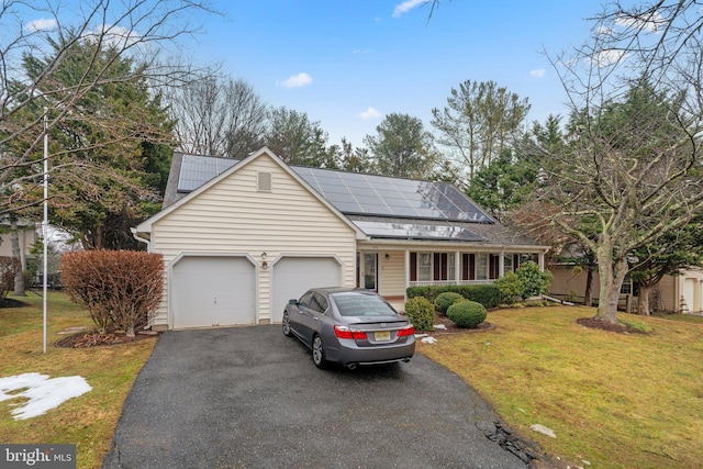 view of front of home with a garage, a front yard, and solar panels