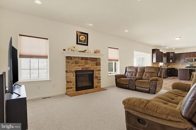 living room with light colored carpet and a stone fireplace