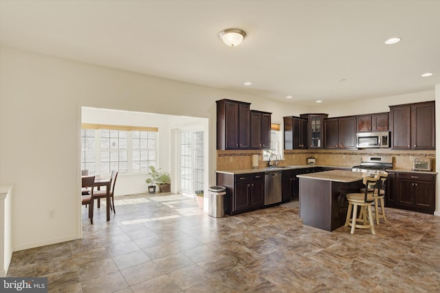 kitchen featuring a breakfast bar, stainless steel appliances, a center island, and dark brown cabinetry