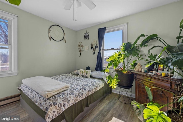 bedroom featuring a baseboard heating unit, hardwood / wood-style flooring, and ceiling fan