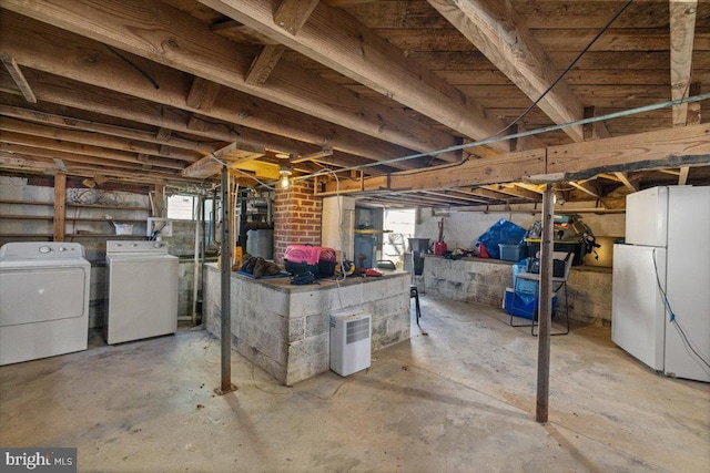 basement with white fridge, plenty of natural light, and washer and clothes dryer