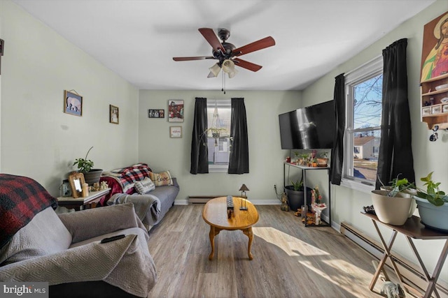 living room featuring ceiling fan, a baseboard heating unit, light hardwood / wood-style floors, and a wealth of natural light