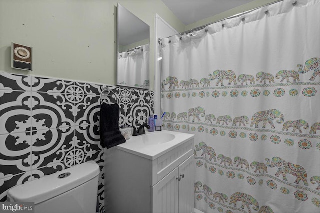 bathroom featuring vanity, toilet, and tile walls