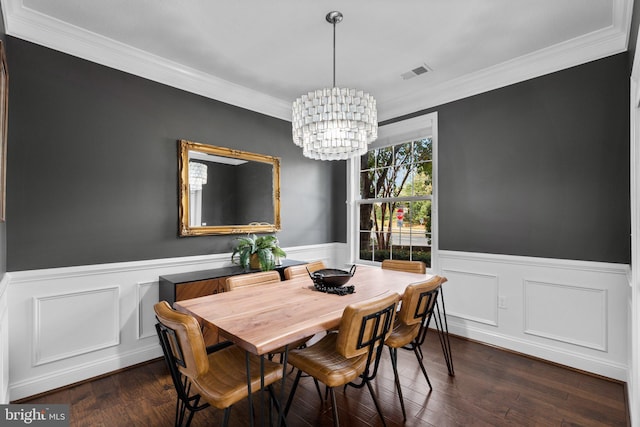 dining space with ornamental molding, dark wood-type flooring, and an inviting chandelier