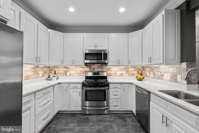 kitchen with tasteful backsplash, sink, white cabinets, and appliances with stainless steel finishes