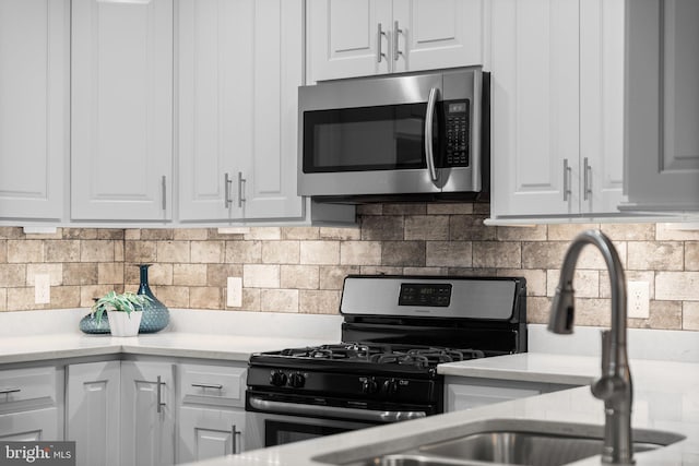 kitchen featuring stainless steel appliances, white cabinets, and backsplash