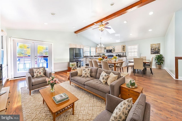 living room with french doors, recessed lighting, light wood finished floors, ceiling fan with notable chandelier, and lofted ceiling with beams