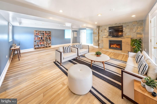 living room featuring a fireplace, recessed lighting, baseboards, and light wood-type flooring