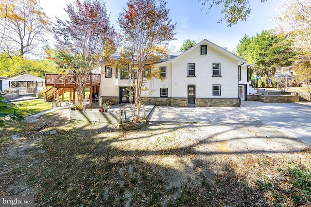 back of property featuring stairway, a deck, and stone siding