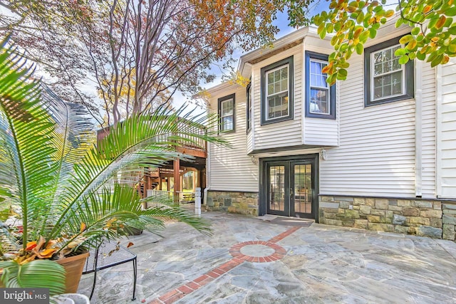 back of property featuring stone siding, french doors, and a patio area