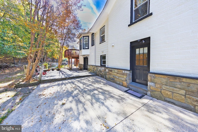 view of side of property featuring stone siding and a patio area