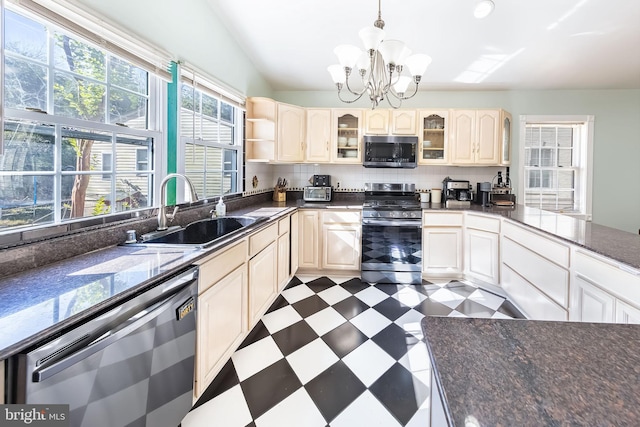 kitchen featuring dark floors, glass insert cabinets, stainless steel appliances, dark countertops, and a sink