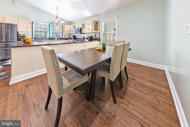 dining room featuring baseboards, dark wood finished floors, an inviting chandelier, and lofted ceiling