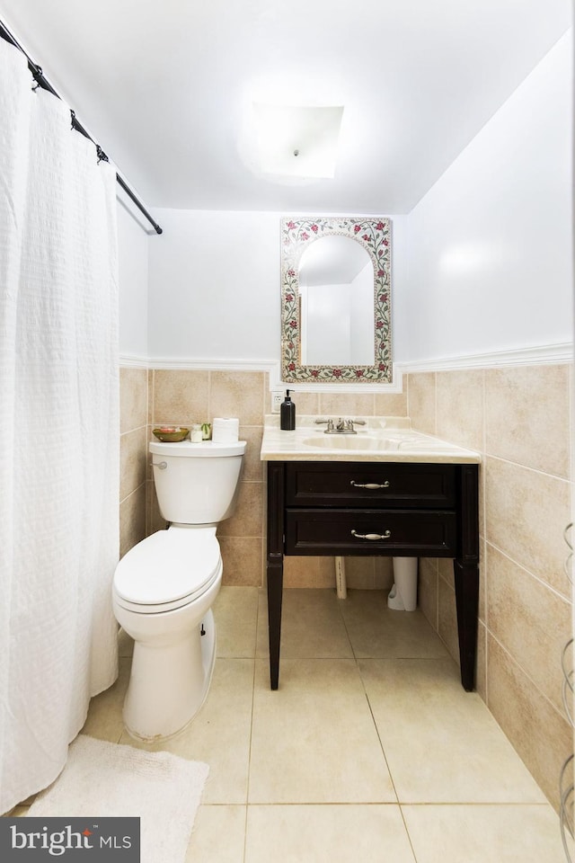 bathroom featuring wainscoting, toilet, tile walls, and tile patterned floors