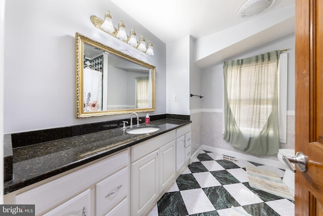 bathroom featuring tile patterned floors, baseboards, toilet, and vanity