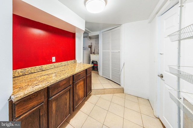 kitchen featuring light tile patterned floors, washer / clothes dryer, and light stone counters