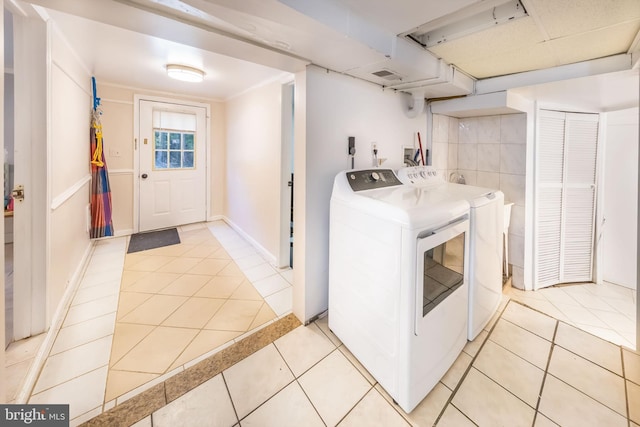 clothes washing area with separate washer and dryer, baseboards, laundry area, and light tile patterned floors