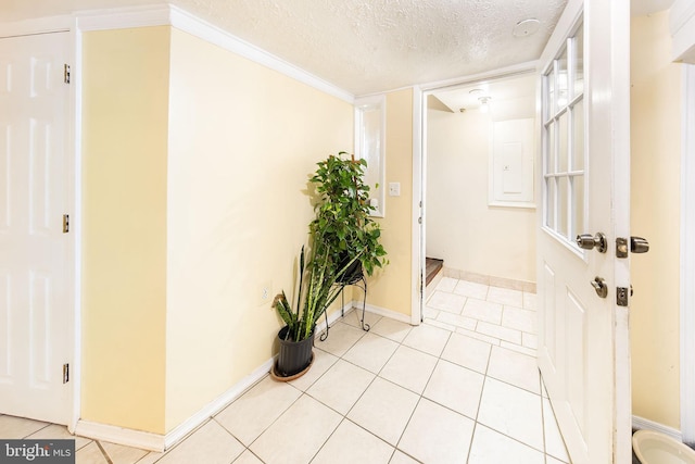 hall with crown molding, light tile patterned floors, baseboards, and a textured ceiling