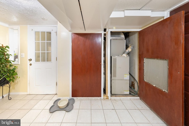 interior space featuring baseboards, light tile patterned floors, and a textured ceiling