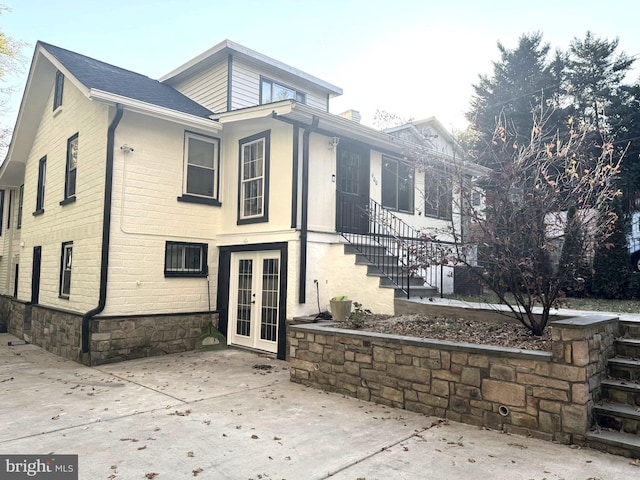 view of front of house featuring brick siding, a chimney, and french doors