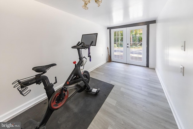 exercise room featuring baseboards, french doors, and light wood-style flooring