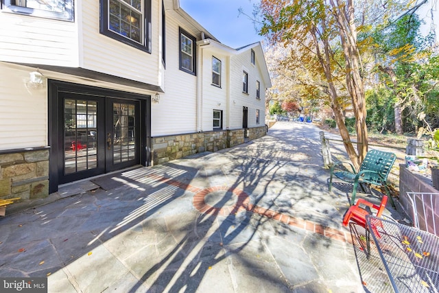 exterior space featuring french doors, fence, and stone siding