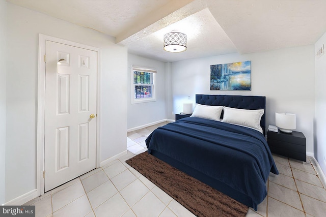 bedroom featuring a textured ceiling, baseboards, and light tile patterned floors