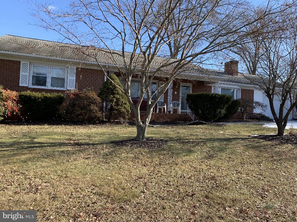 single story home featuring brick siding, a front lawn, and a chimney