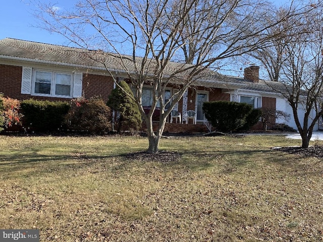 single story home featuring brick siding, a front lawn, and a chimney