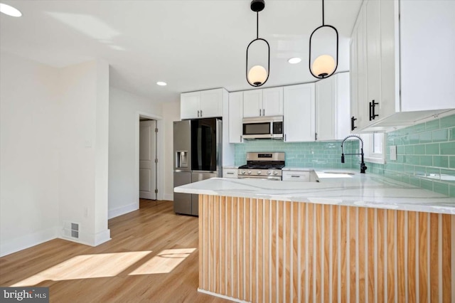 kitchen with sink, hanging light fixtures, stainless steel appliances, white cabinets, and kitchen peninsula