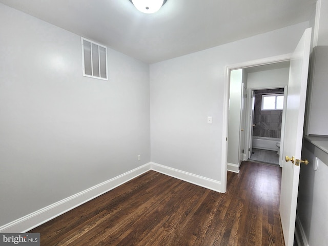 unfurnished room featuring visible vents, dark wood finished floors, and baseboards