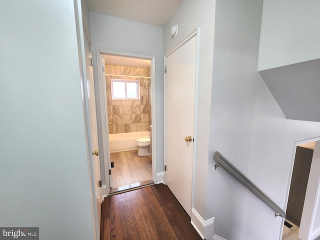 corridor with dark wood-type flooring, baseboards, and an upstairs landing